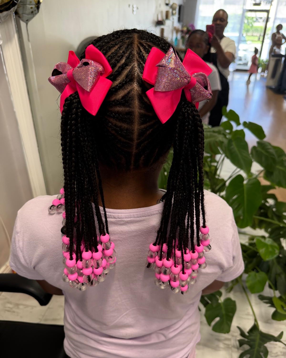 Braids with beads and pink bows styled at Royal Touch Studio